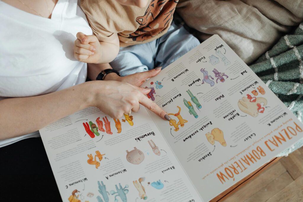 Besišypsantis vaikas kartu su tėvais varto spalvingą vaikišką knygą jaukioje aplinkoje.