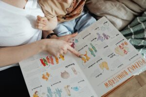 Besišypsantis vaikas kartu su tėvais varto spalvingą vaikišką knygą jaukioje aplinkoje.