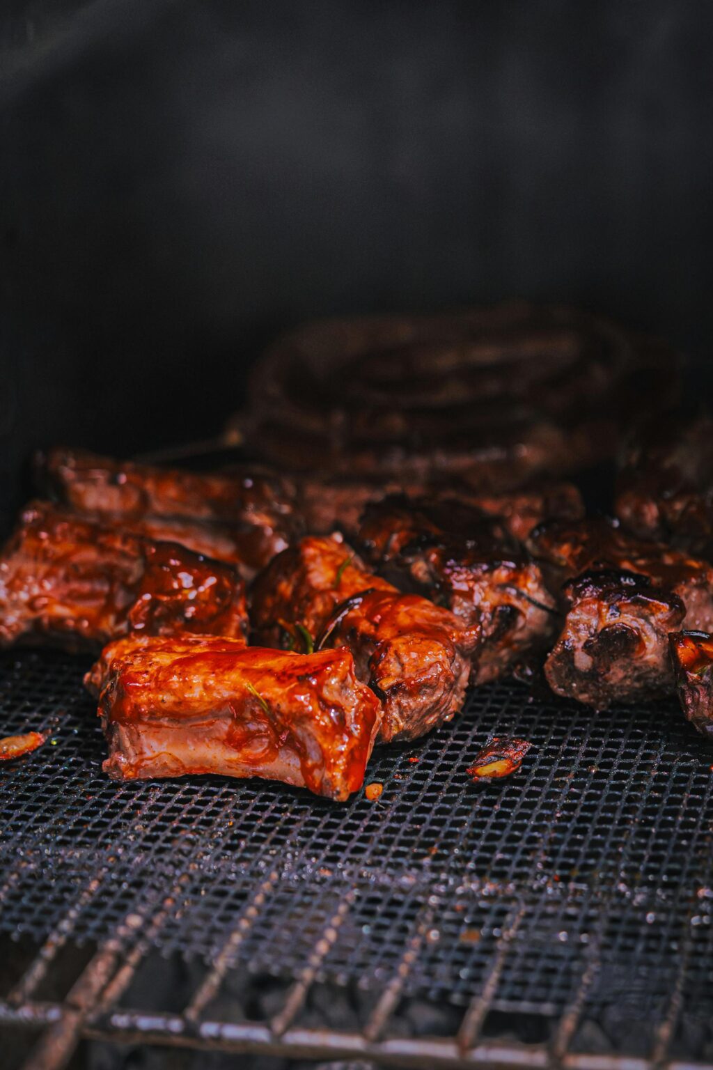 Ant grotelių kepami sultingi kiaulienos šonkauliukai, padengti blizgiu barbekiu padažu.